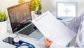Doctor typing information of patient prescription from paperwork medical history form into laptop Royalty Free Stock Photo