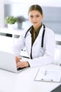 Doctor typing on laptop computer while sitting at the desk in hospital office. Physician woman at work. Data in medicine Royalty Free Stock Photo