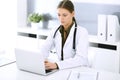 Doctor typing on laptop computer while sitting at the desk in hospital office. Physician woman at work. Data in medicine Royalty Free Stock Photo