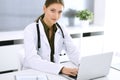 Doctor typing on laptop computer while sitting at the desk in hospital office. Physician woman at work. Data in medicine Royalty Free Stock Photo