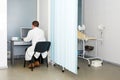 Doctor typing and using his computer in the office. Modern hospital with gynecological chair. Gynecologist waiting for