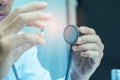 Doctor in uniform holding white and blue capsule pill and stethoscope in office at hospital