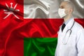 Doctor in uniform with a stethoscope on the background of the silk national flag of Oman, the concept of medical care in the