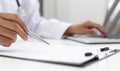 Doctor uses a laptop computer to record patient information and write it on a document to prepare for diagnosis in the room of a m Royalty Free Stock Photo