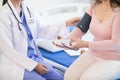 The doctor is using a blood pressure monitor on an elderly patient to check whether the blood pressure is abnormally high or not