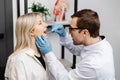 Doctor using inspection spatula to examine patient throat. ENT doctor doing throat exam of a woman. Patient opened her mouth to