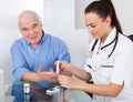 Doctor using lancelet on senior man Royalty Free Stock Photo