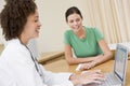 Doctor using laptop with woman in doctor's office Royalty Free Stock Photo