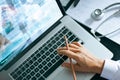 Doctor using laptop working on the desk with stethoscope on healthcare checking report exam of patients Royalty Free Stock Photo