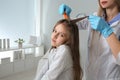 Doctor using nit comb on girl`s hair in clinic. Anti lice Royalty Free Stock Photo