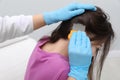 Doctor using nit comb on little girl`s hair indoors. Anti lice treatment