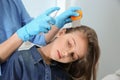 Doctor using nit comb and spray on girl`s hair. Anti lice treatment