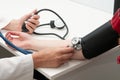Doctor using sphygmomanometer with stethoscope checking blood pressure to a patient in clinic Royalty Free Stock Photo