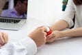 Doctor using stethoscope checking young female patient holding heart as symbolic of medical care Royalty Free Stock Photo