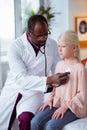 Doctor using stethoscope while listening to lungs of girl