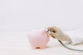 Doctor using stethoscope to check pink piggy bank. Concept check saving money and financial sustainability Royalty Free Stock Photo