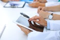 Doctor using tablet computer at medical meeting, closeup. Group of colleagues at the background Royalty Free Stock Photo