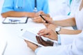 Doctor using tablet computer at medical meeting, closeup. Group of colleagues at the background Royalty Free Stock Photo