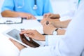 Doctor using tablet computer at medical meeting, closeup. Group of colleagues at the background Royalty Free Stock Photo