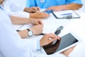 Doctor using tablet computer at medical meeting, closeup. Group of colleagues at the background Royalty Free Stock Photo