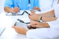 Doctor using tablet computer at medical meeting, closeup. Group of colleagues at the background Royalty Free Stock Photo
