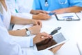 Doctor using tablet computer at medical meeting, closeup. Group of colleagues at the background Royalty Free Stock Photo