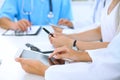 Doctor using tablet computer at medical meeting, closeup. Group of colleagues at the background Royalty Free Stock Photo