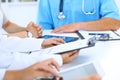 Doctor using tablet computer at medical meeting, closeup. Group of colleagues at the background Royalty Free Stock Photo