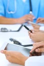 Doctor using tablet computer at medical meeting, closeup. Group of colleagues at the background Royalty Free Stock Photo