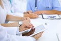 Doctor using tablet computer at medical meeting, closeup. Group of colleagues at the background Royalty Free Stock Photo