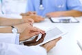 Doctor using tablet computer at medical meeting, closeup. Group of colleagues at the background Royalty Free Stock Photo