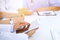 Doctor using tablet computer at medical meeting, closeup. Group of colleagues at the background Royalty Free Stock Photo