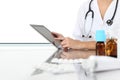 Doctor using tablet in office with drugs on desk Royalty Free Stock Photo