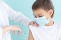 Doctor vaccinates the child in a medical mask against the infection,