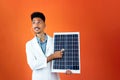 Doctor or Veterinarian Isolated on Orange Background. Black Young Doctor Medical Resident With Stethoscope Holding Solar Panel Royalty Free Stock Photo
