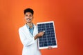 Doctor or Veterinarian Isolated on Orange Background. Black Young Doctor Medical Resident With Stethoscope Holding Solar Panel Royalty Free Stock Photo