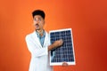 Doctor or Veterinarian Isolated on Orange Background. Black Young Doctor Medical Resident With Stethoscope Holding Solar Panel Royalty Free Stock Photo