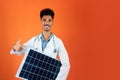 Doctor or Veterinarian Isolated on Orange Background. Black Young Doctor Medical Resident With Stethoscope Holding Solar Panel Royalty Free Stock Photo