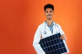 Doctor or Veterinarian Isolated on Orange Background. Black Young Doctor Medical Resident With Stethoscope Holding Solar Panel Royalty Free Stock Photo