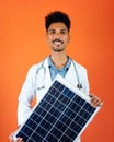 Doctor or Veterinarian Isolated on Orange Background. Black Young Doctor Medical Resident With Stethoscope Holding Solar Panel Royalty Free Stock Photo