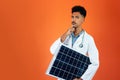 Doctor or Veterinarian Isolated on Orange Background. Black Young Doctor Medical Resident With Stethoscope Holding Solar Panel Royalty Free Stock Photo