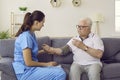 Physician visits senior man at home and measures his blood pressure with tonometer Royalty Free Stock Photo