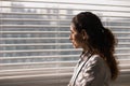 Young latin woman medic therapist stand by window with smile