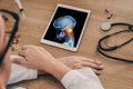 Doctor watching a digital tablet with x-ray of skull with pain in the top of the neck. Migraine headache or trauma concept