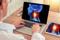 Doctor watching a laptop with x-ray of a 3D skull head with pain relief in the neck in a medical office. Headache migraine concept Royalty Free Stock Photo