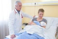 Doctor watching over mother with newborn baby in hospital bed Royalty Free Stock Photo