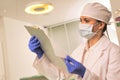 Doctor wearing face mask and cap while examining medical result at clinic