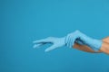 Doctor wearing medical gloves on light blue background, closeup. Space for text Royalty Free Stock Photo