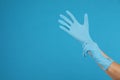 Doctor wearing medical gloves on light blue background, closeup. Space for text Royalty Free Stock Photo