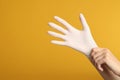Doctor wearing medical gloves on yellow background, closeup. Space for text Royalty Free Stock Photo